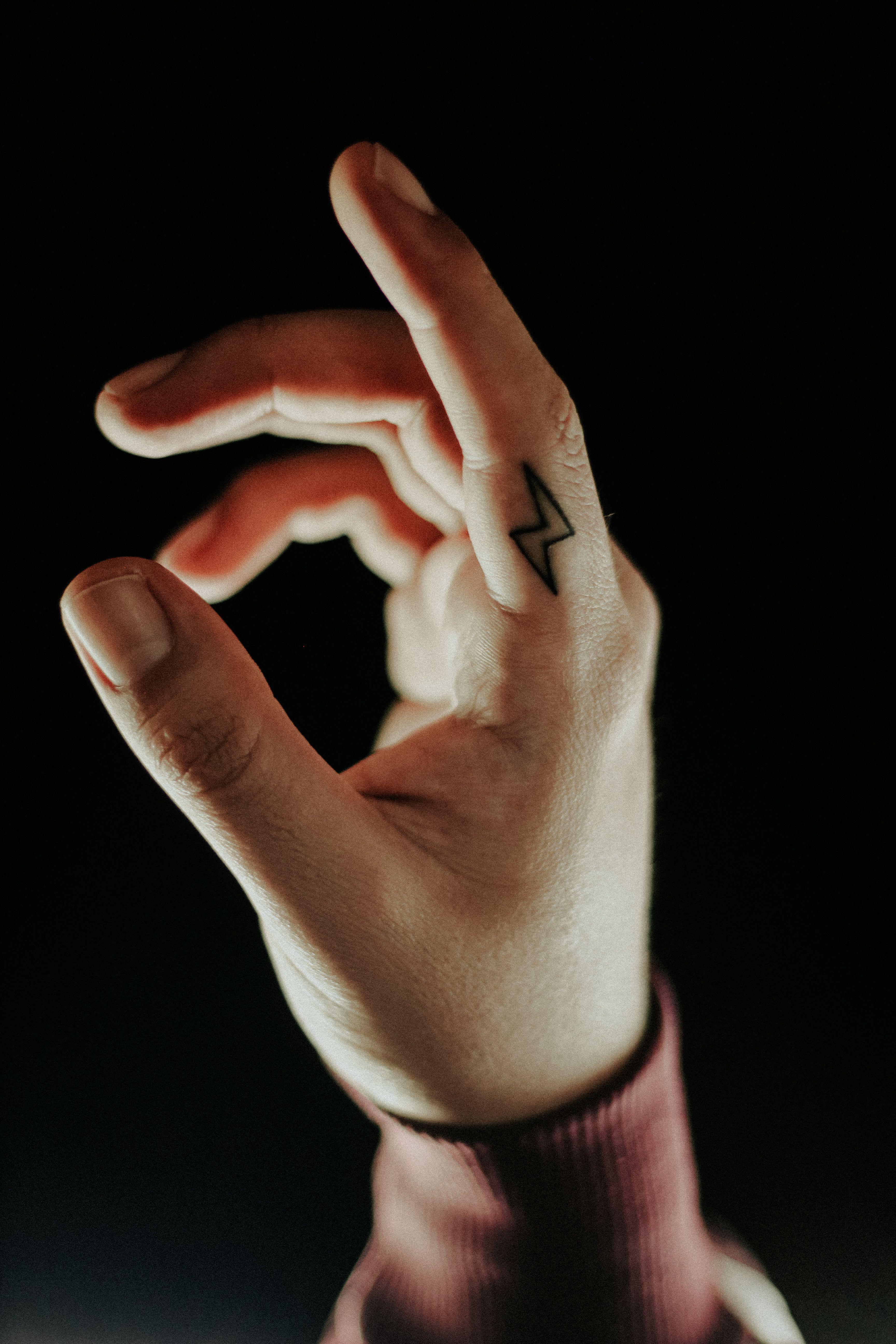 Tatuagem de raio no dedo médio em fundo preto